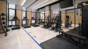 Un gimnasio moderno con cintas de correr, máquinas de pesas y pesas sueltas.
