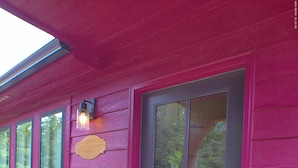 Una casa con una puerta principal oscura, un letrero de bienvenida y un accesorio de iluminación sobre la puerta.