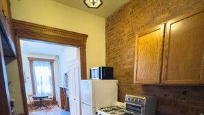 A kitchen with wooden cabinets, a gas stove, a microwave, and a refrigerator.