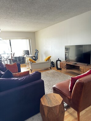 A modern living room with a sofa, a coffee table, a TV, and a desk with a computer.
