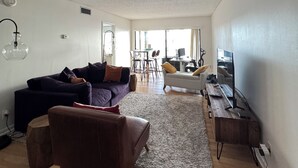 Un salon moderne avec un canapé, un fauteuil et un téléviseur posé sur un meuble en bois.