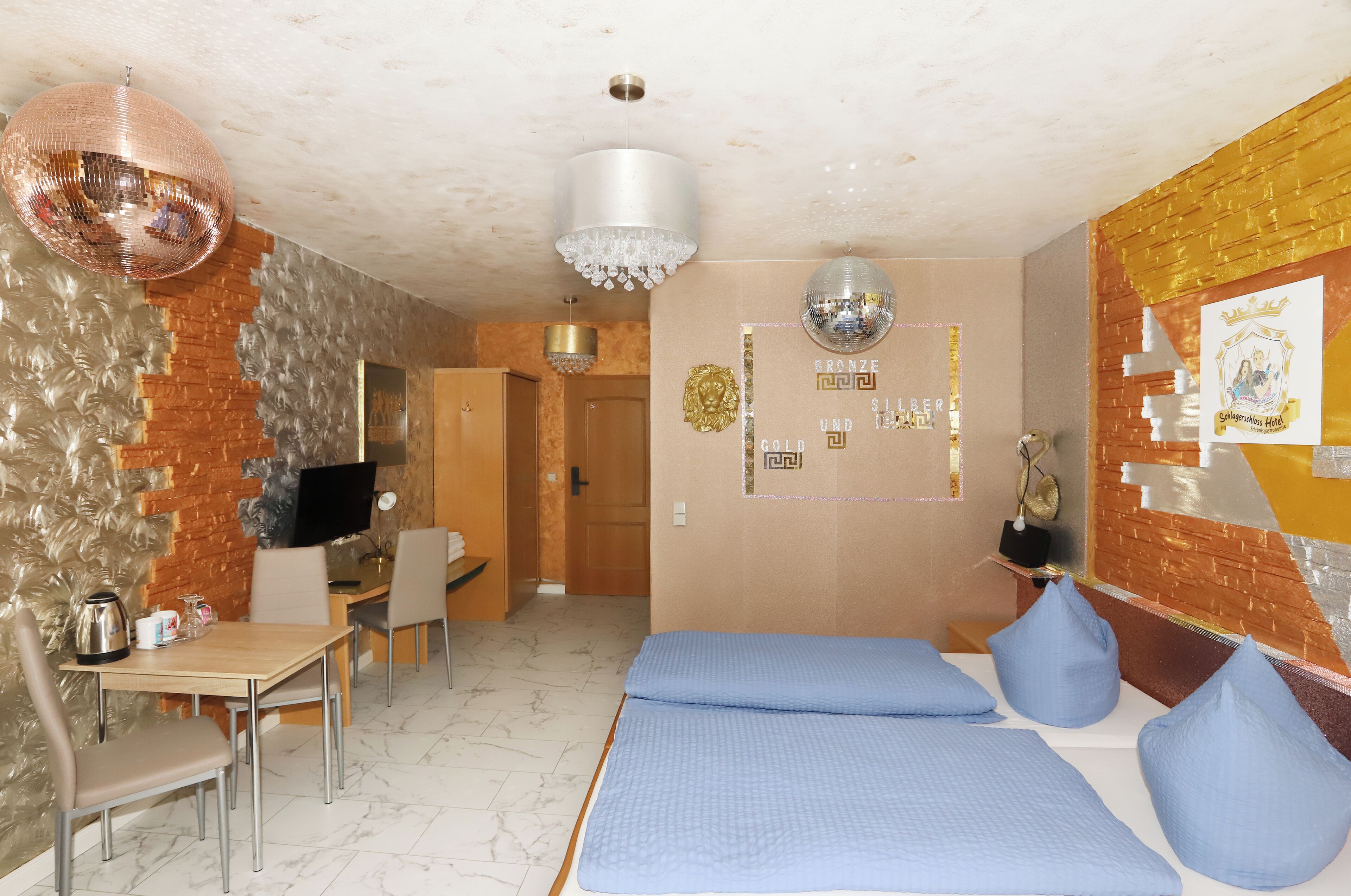 Una habitación de hotel con pared de ladrillo, una araña, una cama con ropa de cama azul y un escritorio con una silla.