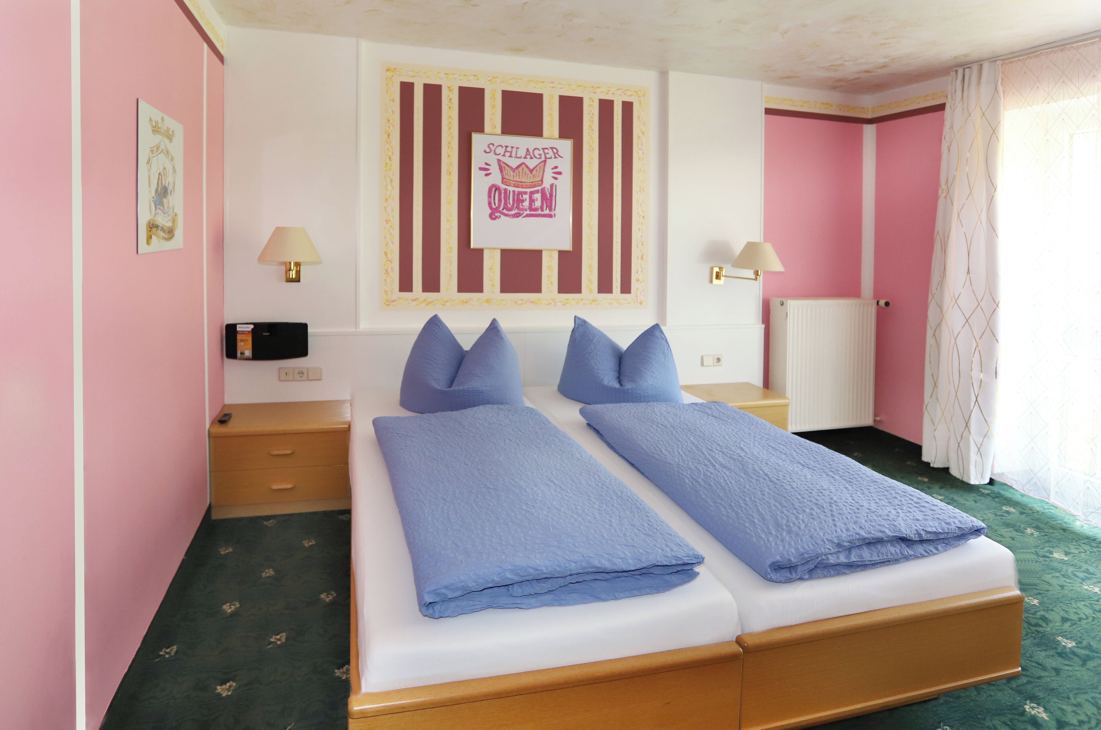Ein Doppelbett mit blauer Bettwäsche, ein Nachttisch, eine Lampe und ein gerahmtes Bild an der Wand.