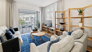 Een moderne woonkamer met een bank, een salontafel, een televisie en een houten boekenkast.