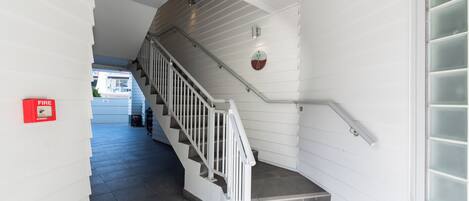 A staircase with white railings and a fire alarm on the wall.