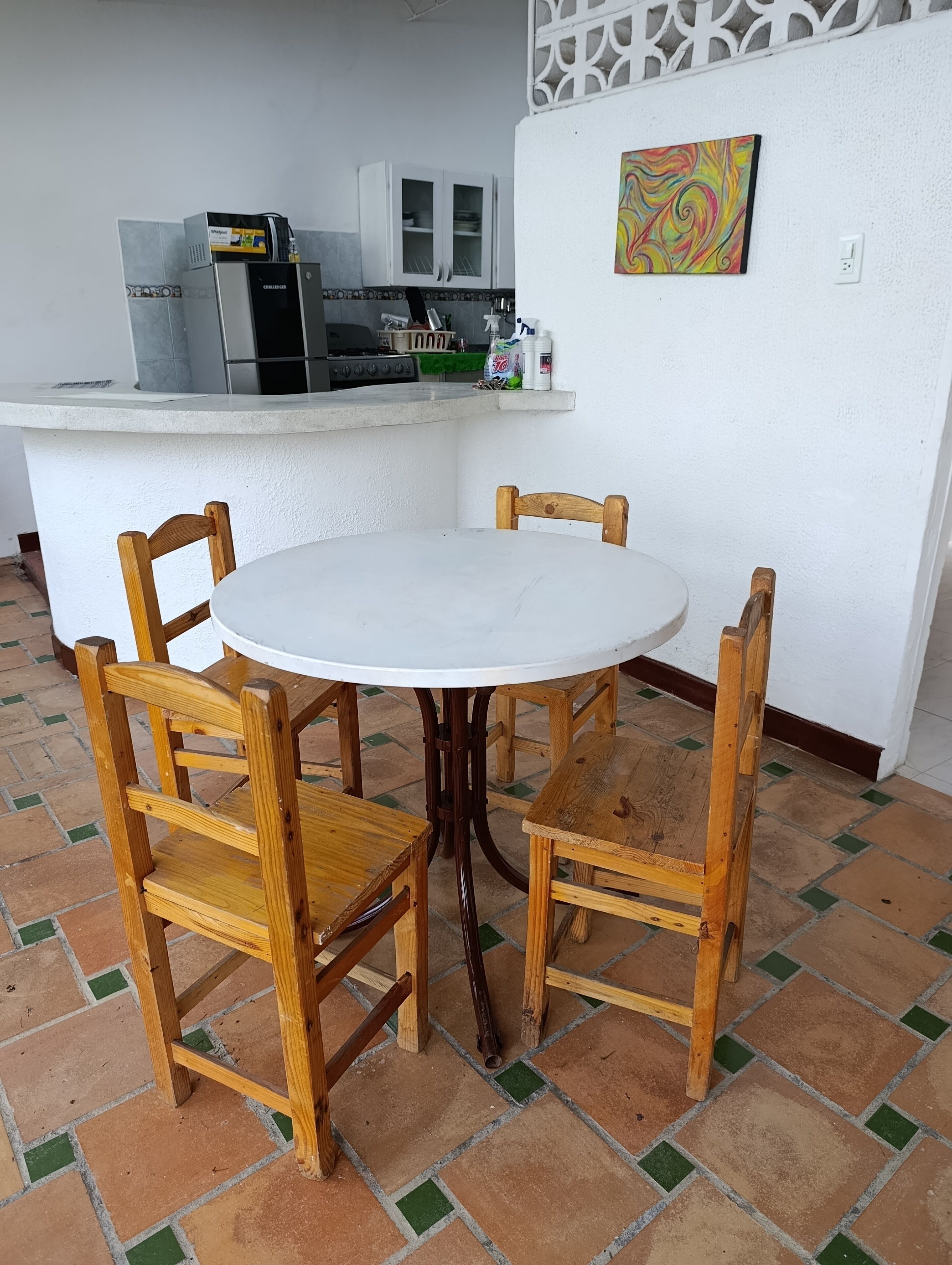 Ein runder Holztisch mit vier Stühlen in einer Küche mit Fliesenboden.