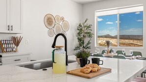 A kitchen with a large island, a potted plant, a glass pitcher of lemonade, and a cutting board with food. - Lakeview Oasis at Powell - Heated Pool+Lake Views+Game Room (Page)