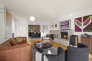 A modern living room with a leather sofa, a coffee table, a fireplace, and a TV.