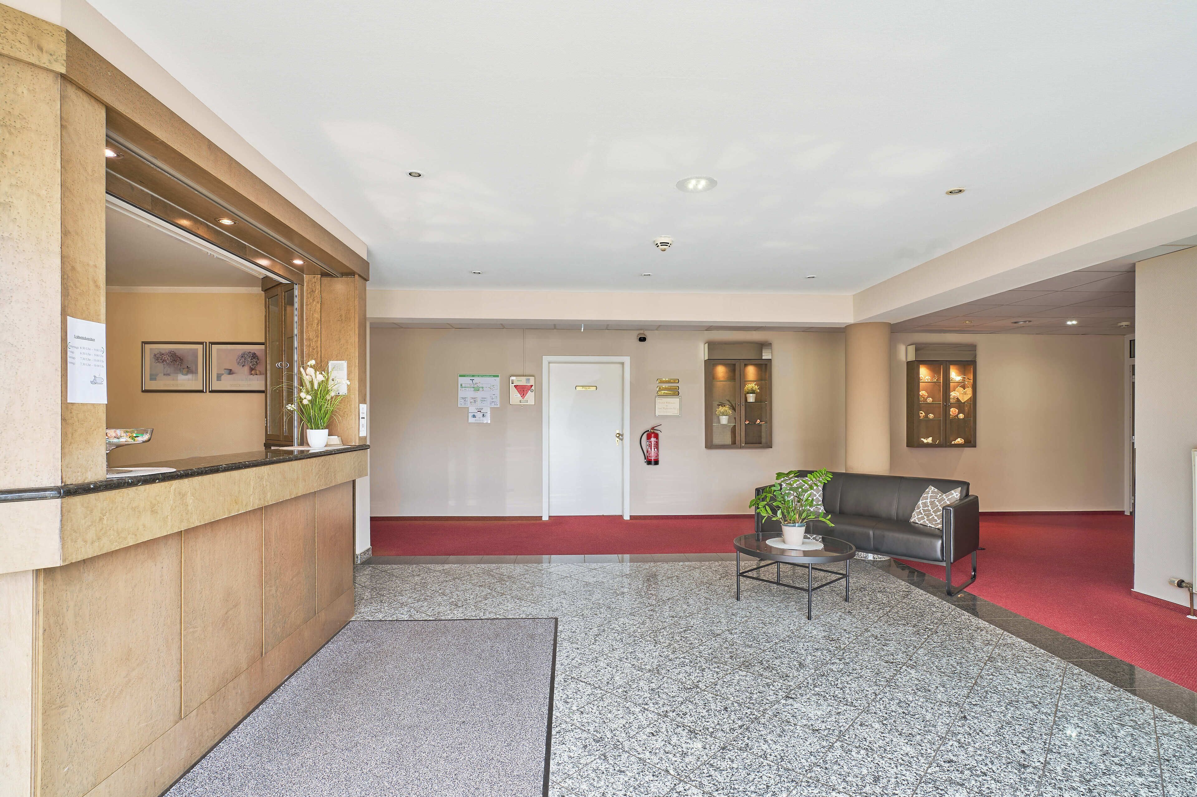 Et receptionsområde med skranke, sofa, sofabord og brandslukker.