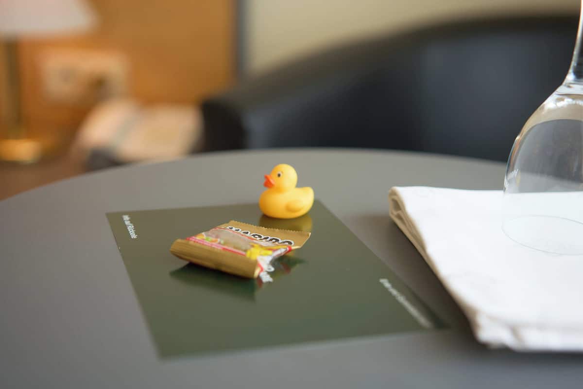 Une table avec un canard en caoutchouc, un petit paquet et un verre d’eau.