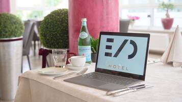 A laptop on a table with a glass of water, a cup, and a bottle of Pellegrino water.