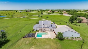 A large house with a swimming pool, fenced yard, and multiple buildings.