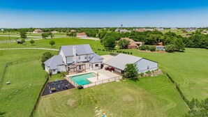 A large house with a swimming pool, a patio, and a fenced yard.