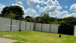 A well-maintained backyard with a soccer goal, a patio area, and a fenced enclosure.