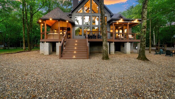 A large, modern house with a spacious deck, multiple windows, and a stone foundation.