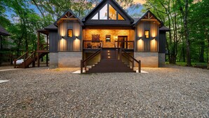 A two-story log cabin with a stone facade, wooden exterior, and a staircase leading to the entrance.