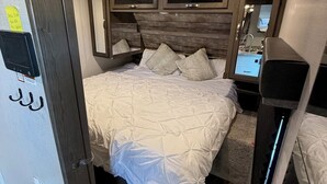 Un dormitorio compacto con cama, un tragaluz pequeño, un espejo y televisión integrada.