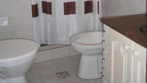 Un baño con dos inodoros, una cortina de ducha y paredes de azulejos.