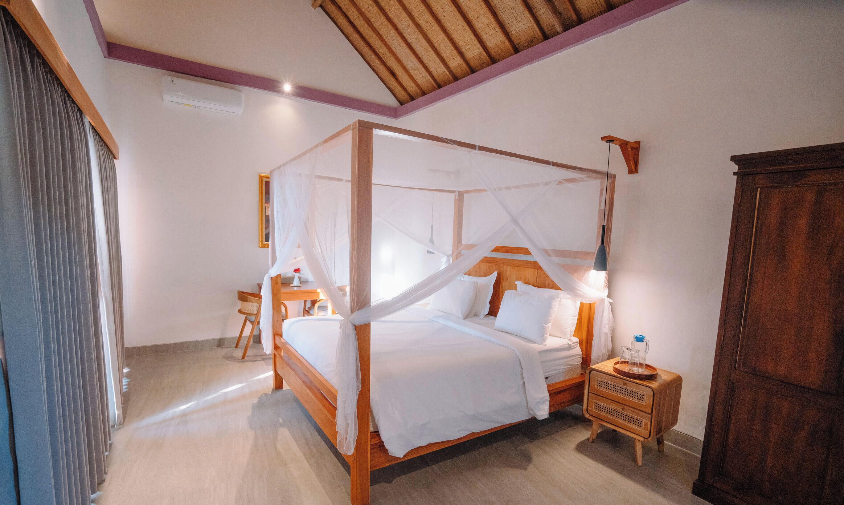 A four-poster bed with a canopy, a bedside table with a lamp, and a wooden wardrobe.