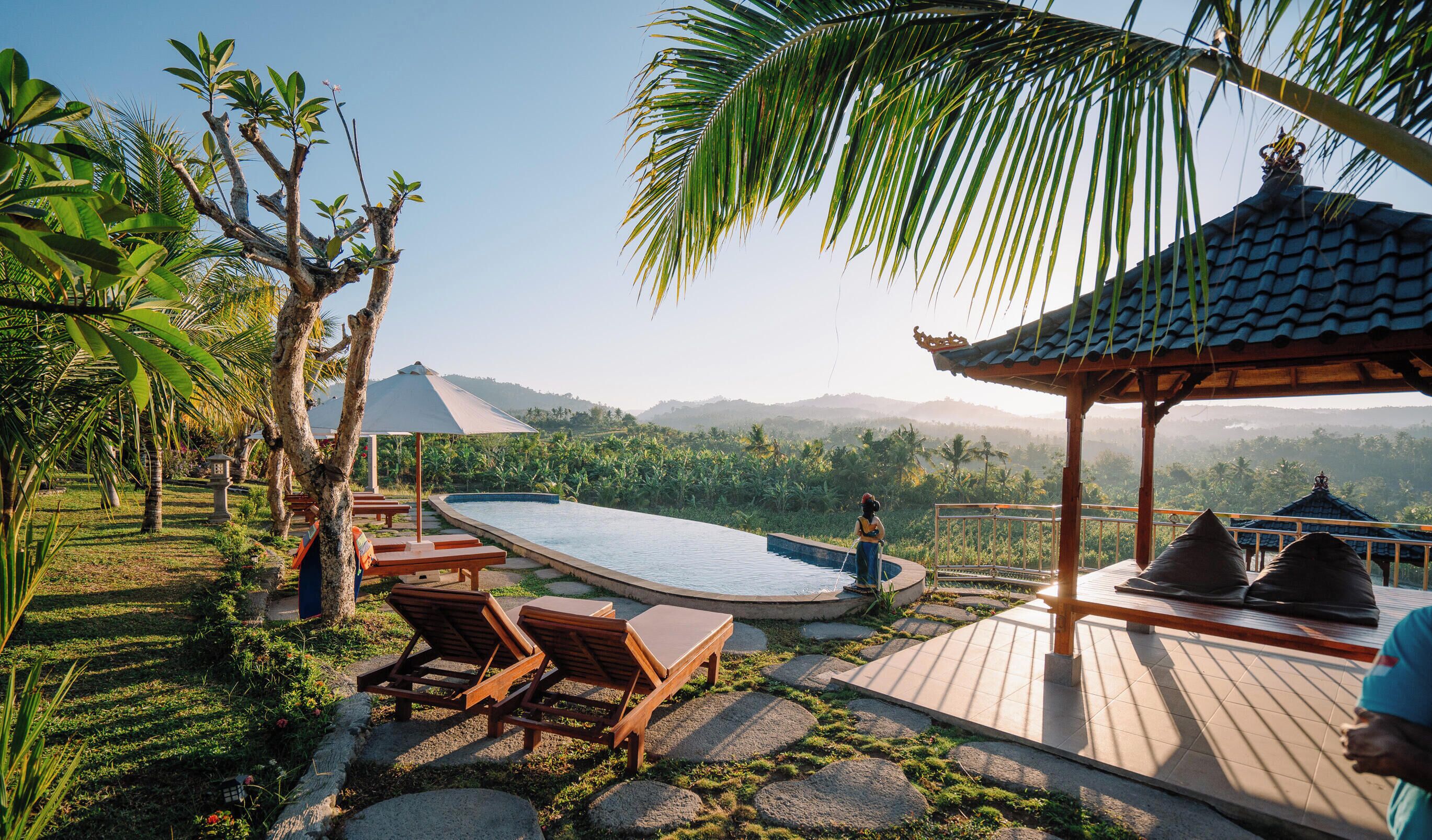 A pool area with lounge chairs, a gazebo, and a view of the surrounding landscape.