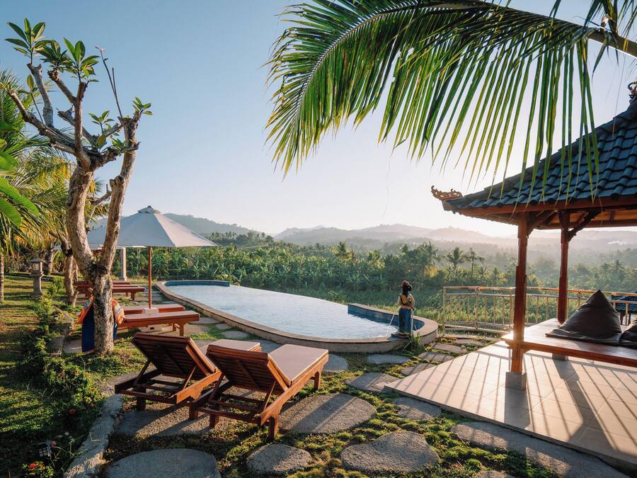 A pool area with lounge chairs, a gazebo, and a view of the surrounding landscape.