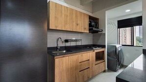 A modern kitchen with wooden cabinets, a black countertop, stainless steel appliances, and a window with a view of buildings.