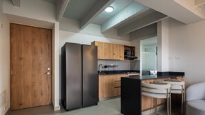 A modern kitchen with wooden cabinets, a black refrigerator, and a microwave.