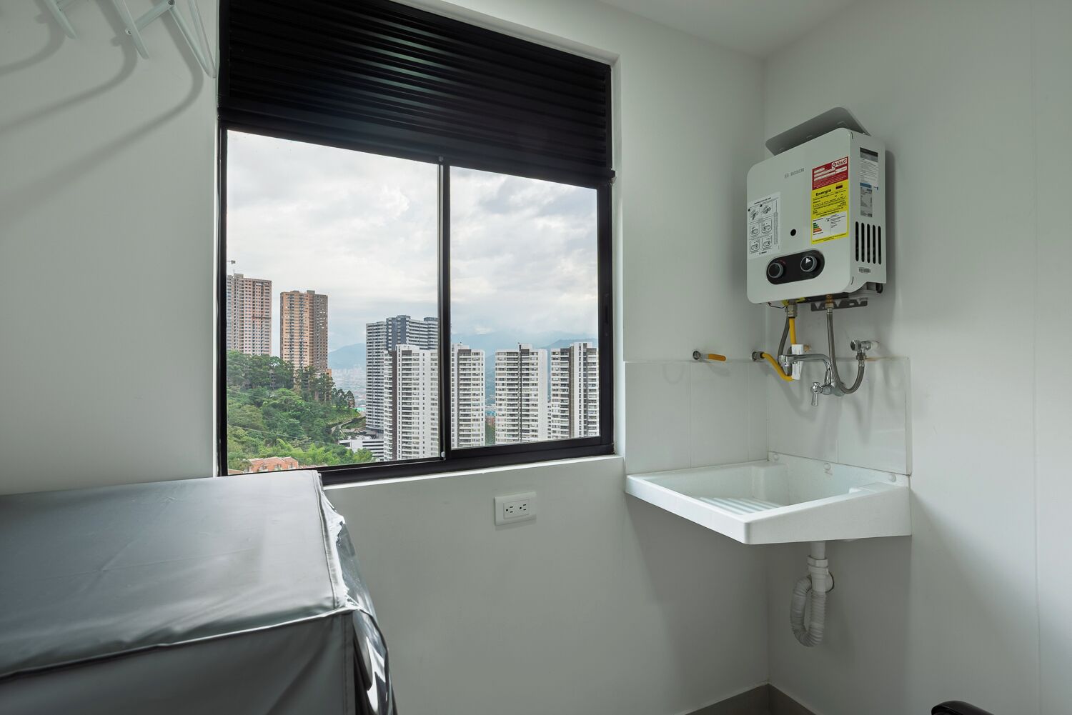 A bathroom with a window, a white sink, and a water heater.