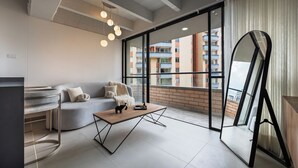 A modern living room with a sofa, coffee table, and a large window overlooking a cityscape.
