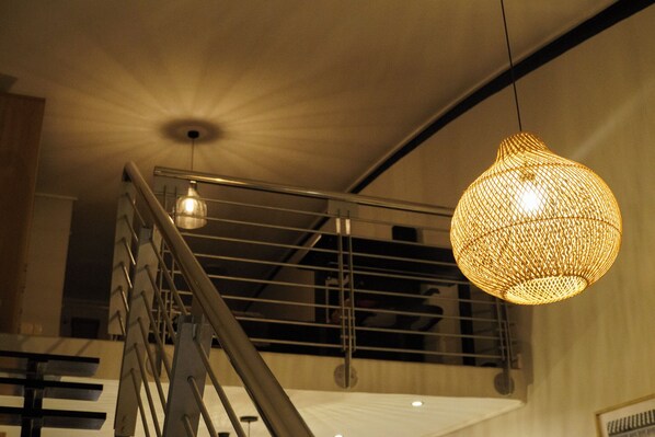 Una escalera con barandilla de metal y un colgante de luz tejido.