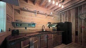 Une cuisine rustique avec des murs en bois, un réfrigérateur noir et un plan de travail en bois.