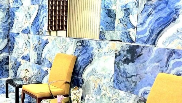 A room with a marble-patterned floor and walls, featuring two yellow chairs and a glass table. - Masal Otel (Burhaniye)