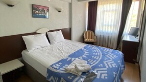 A hotel room with a bed, a chair, a desk, and a window with curtains. - Masal Otel (Burhaniye)