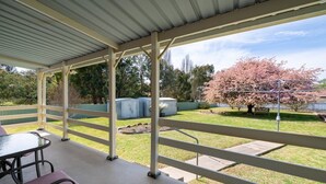 A covered patio area with a table and chairs, a fenced yard with a tree, and a shed in the background. - 🏁 Racetrack – Charming Family Home Near Mount Panorama (South Bathurst)