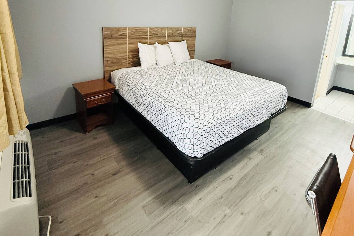 A bedroom with a bed, wooden headboard, bedside tables, and a ceiling light.