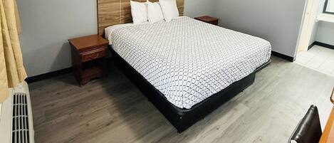 A bedroom with a bed, wooden headboard, bedside tables, and a ceiling light.