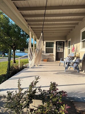 A covered porch with a hammock, outdoor seating, and a view of a lake.