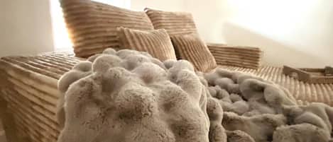 Un lit avec une couverture épaisse et à texture particulière, ainsi que plusieurs oreillers.