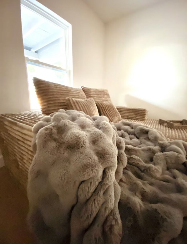 Ein Bett mit einer dicken, gemusterten Decke und mehreren Kissen.