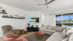 Un salon moderne avec un canapé, des fauteuils, une table basse et un téléviseur fixé au mur.