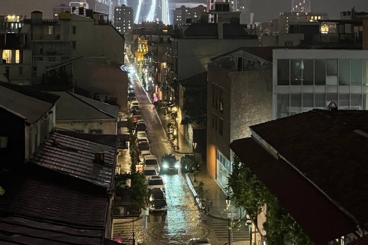 A nighttime cityscape with illuminated buildings and a street.
