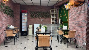Un café chaleureux aux murs de briques, au sol carrelé et aux chaises en osier.