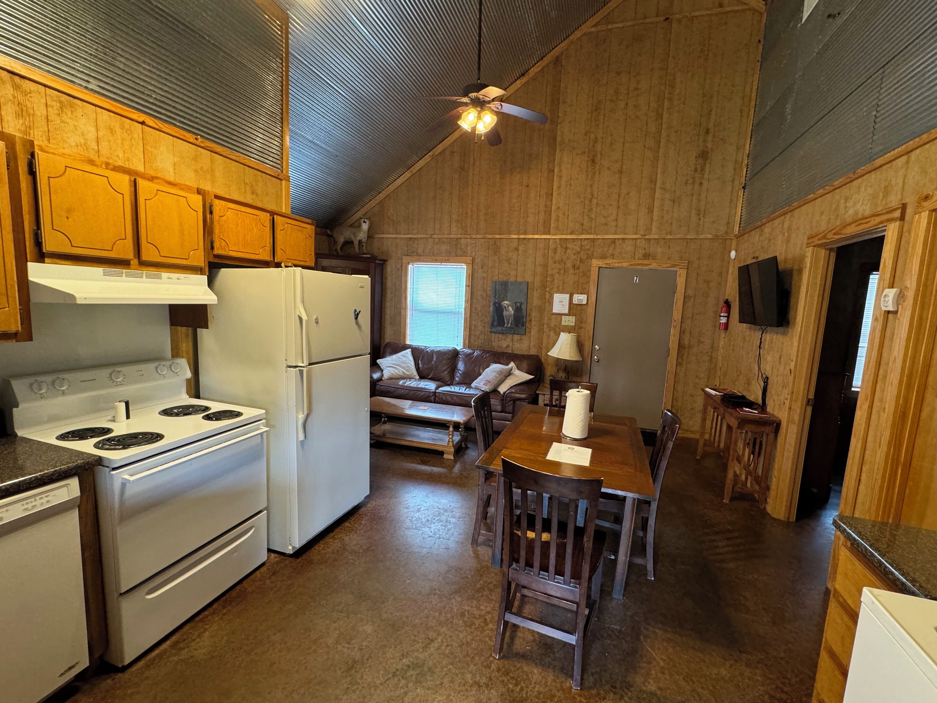 A kitchen with wooden cabinets, a stove, refrigerator, and a dining area with a table and chairs.