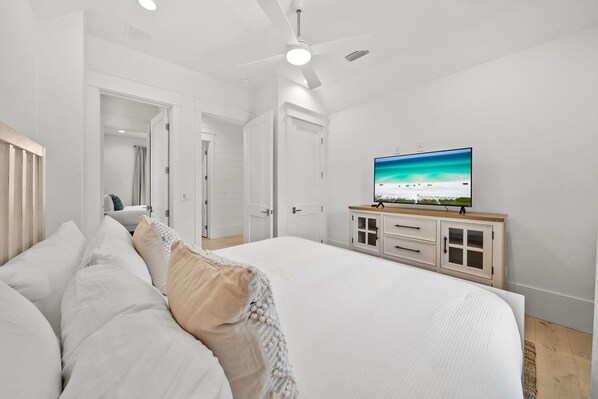 A bedroom with a bed, a ceiling fan, a TV, and a cabinet.