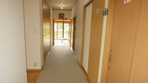 Un couloir avec des portes en bois, un banc et une porte sur laquelle est apposée une pancarte.