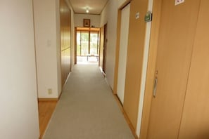 Un pasillo con puertas de madera, un banco y una puerta con un cartel.