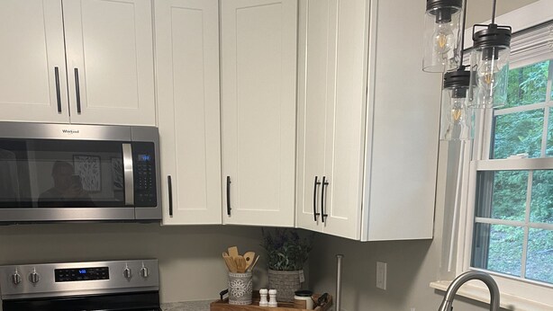 A modern kitchen with white cabinets, stainless steel appliances, granite countertops, and a window with a view of greenery. - Charming 2-bedroom house, quiet neighborhood, in SoKno minutes from downtown (Knoxville)