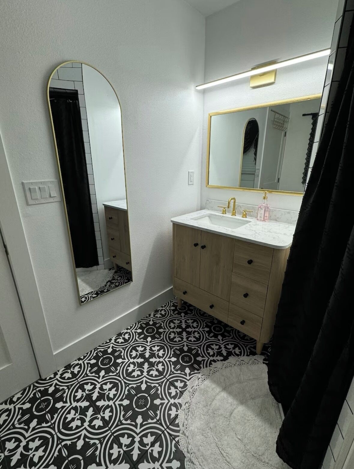A bathroom with a white sink, a mirror, and patterned floor tiles.