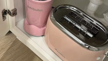 Una kitchenette con una licuadora rosa y un tostador.