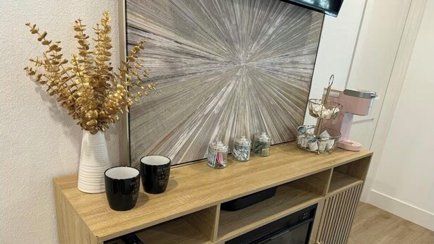 Una consola de madera con chimenea, un jarrón decorativo y diversos objetos encima.